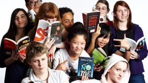 group of teenagers all holding books up in front of the camera